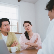 保険会社員に疑いの目を向ける夫婦の写真